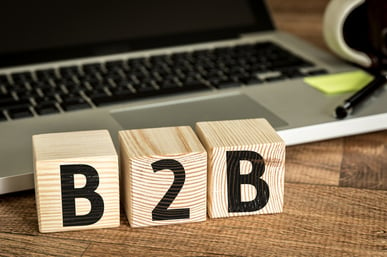 “B2B” spelled out on wooden building blocks in front of an open laptop